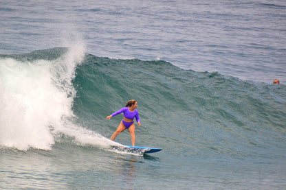 Women surfing on a wave in the ocean wearing trend ripple long sleeve set